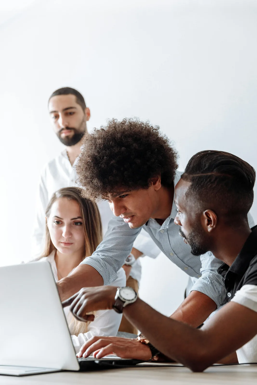 A diverse group collaborating around a laptop.
