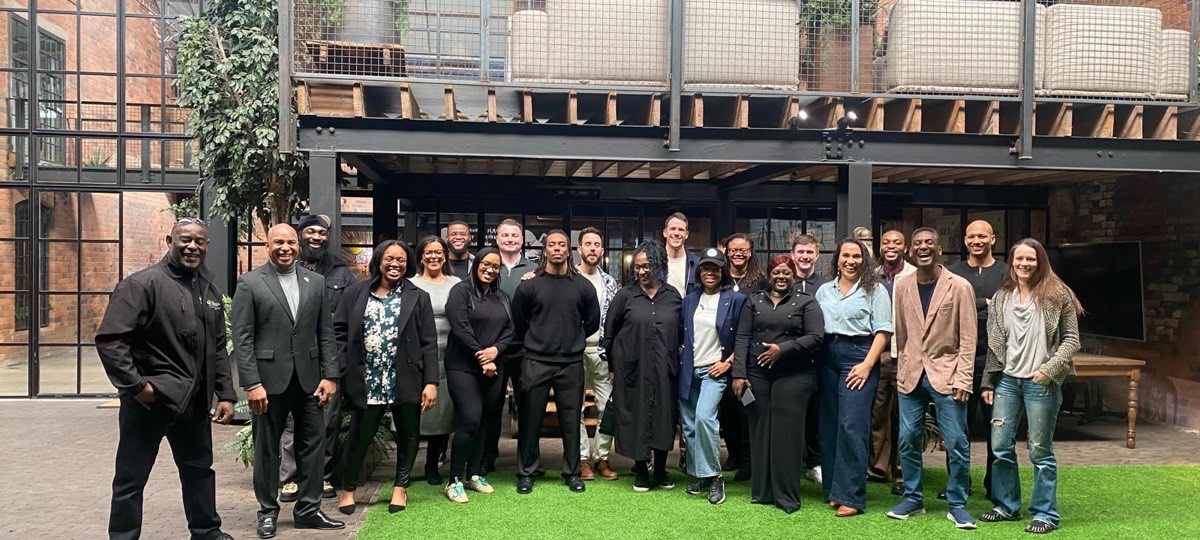 A large group of FairBuild founders, operators and partners gathered together and smiling after a community session.