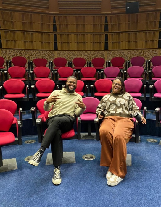 Two FairBuild founders laughing together in the raked seating of a shared venue.