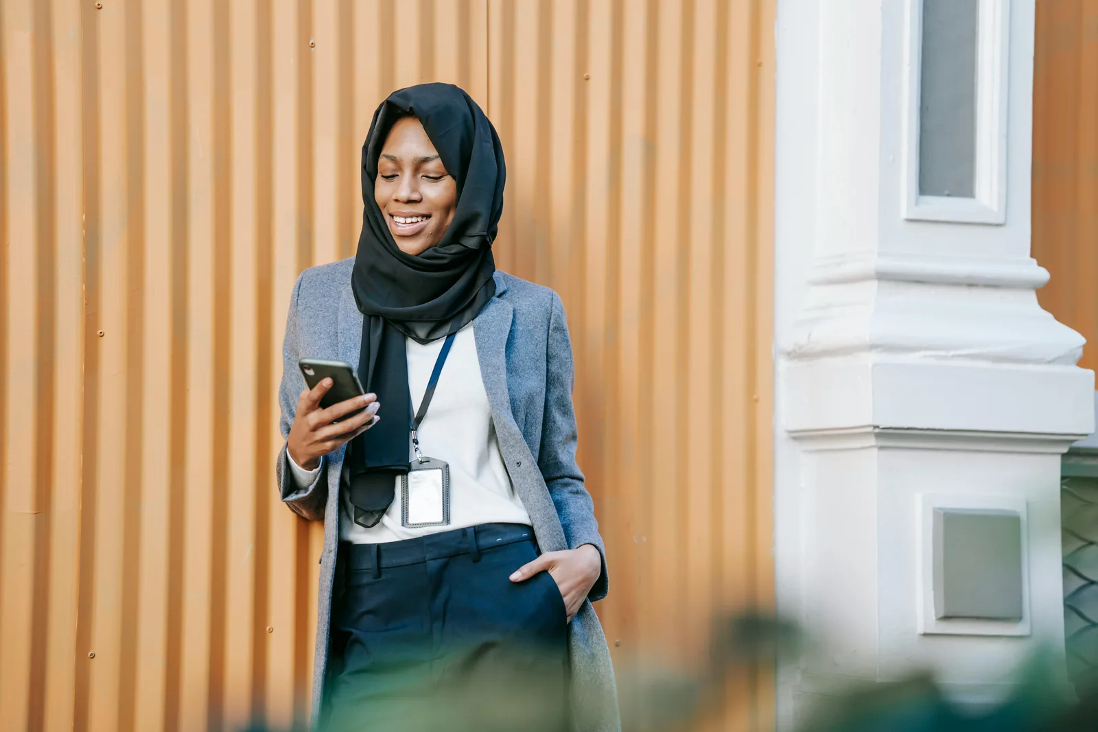 A professional using her phone outside a workplace.