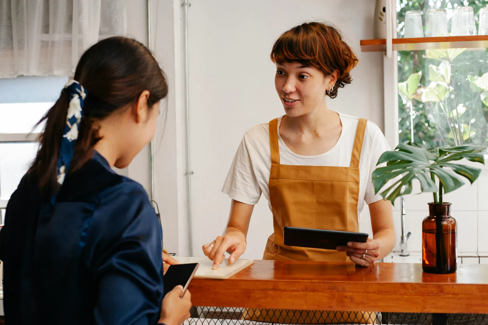 A shopkeeper helping a customer across the counter.
